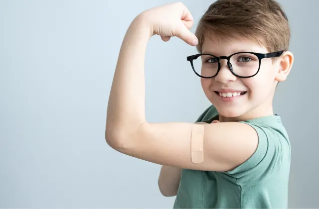 Young boy with band aid where he got a vaccine.