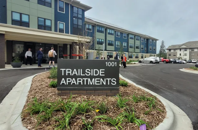 A sign for Trailside Apartments with the building in the background