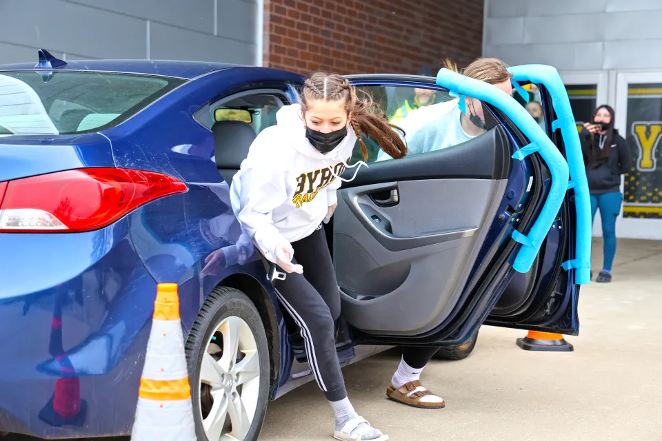 Student running around car as a part of the seat belt challenge 