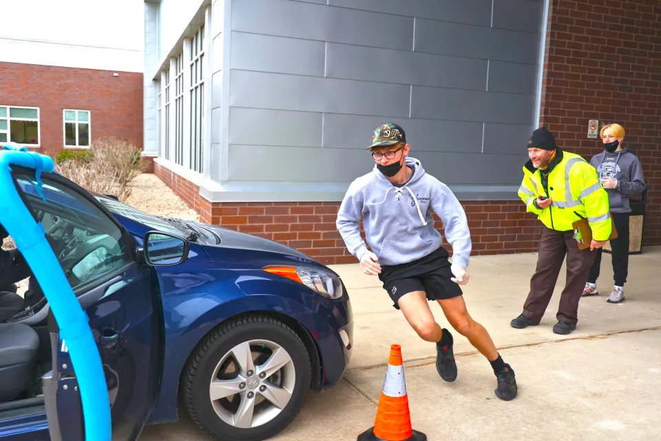 Student running around car as a part of the seat belt challenge 