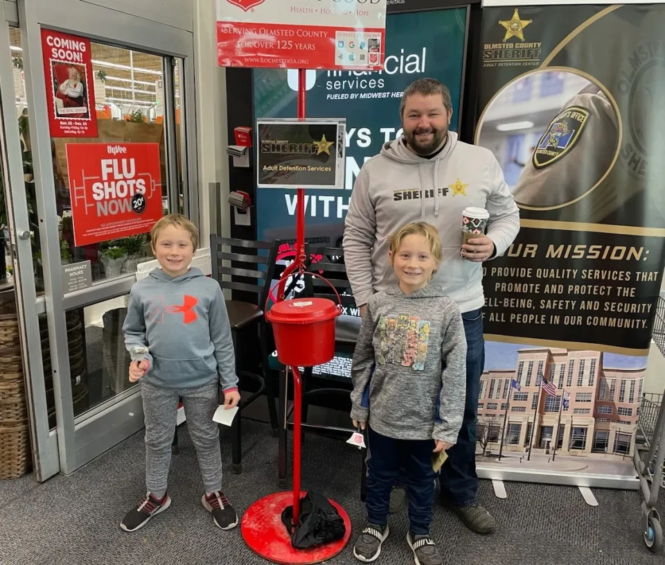 Staff member and family ring bells for the Salvation Army at Hyvee