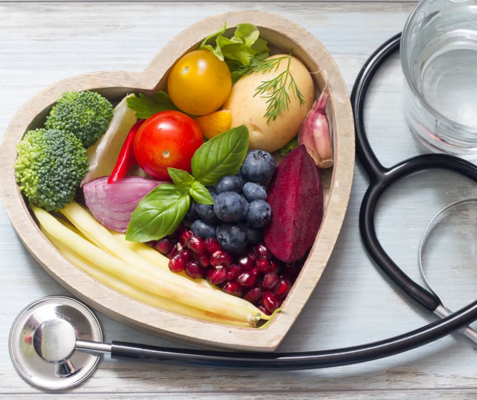 Healthy food in a heart-shaped bowl. A Stethoscope around it.