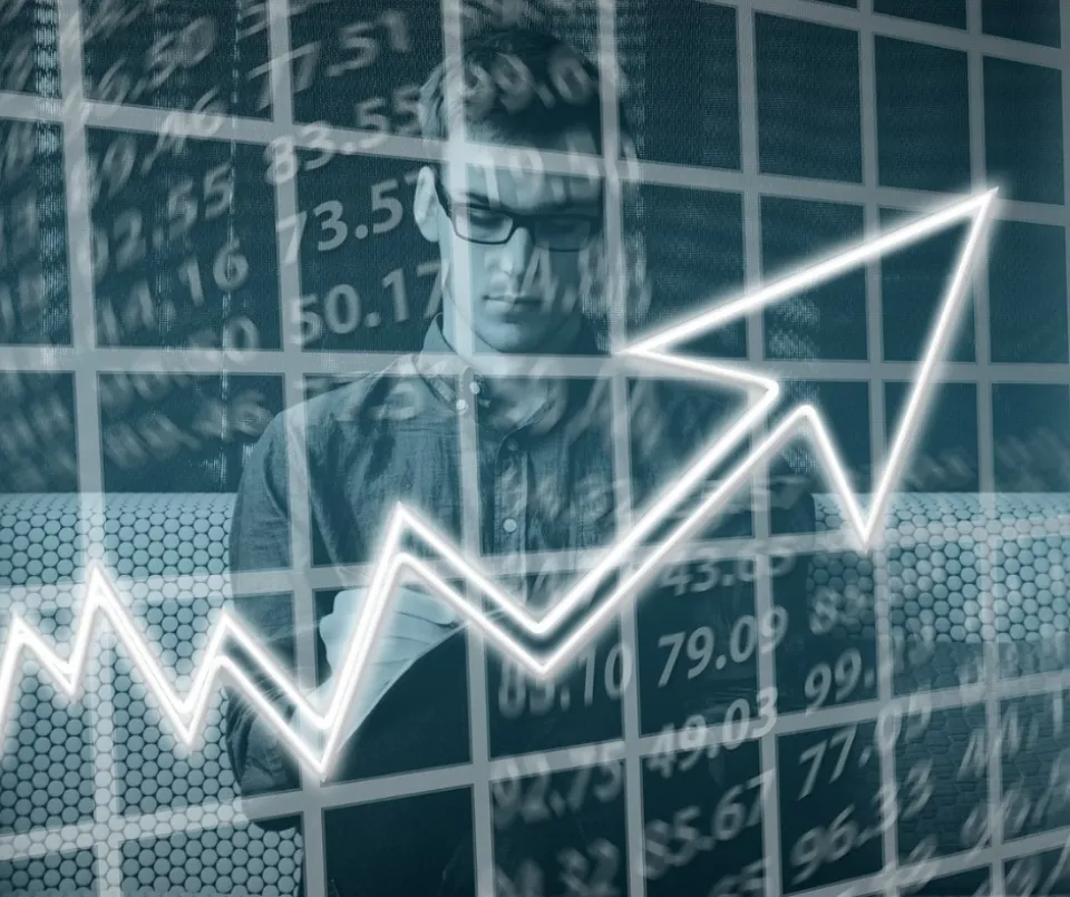 Person analyzing financial data with an upward trending graph superimposed in the foreground, suggesting a focus on stock market analysis or economic growth.