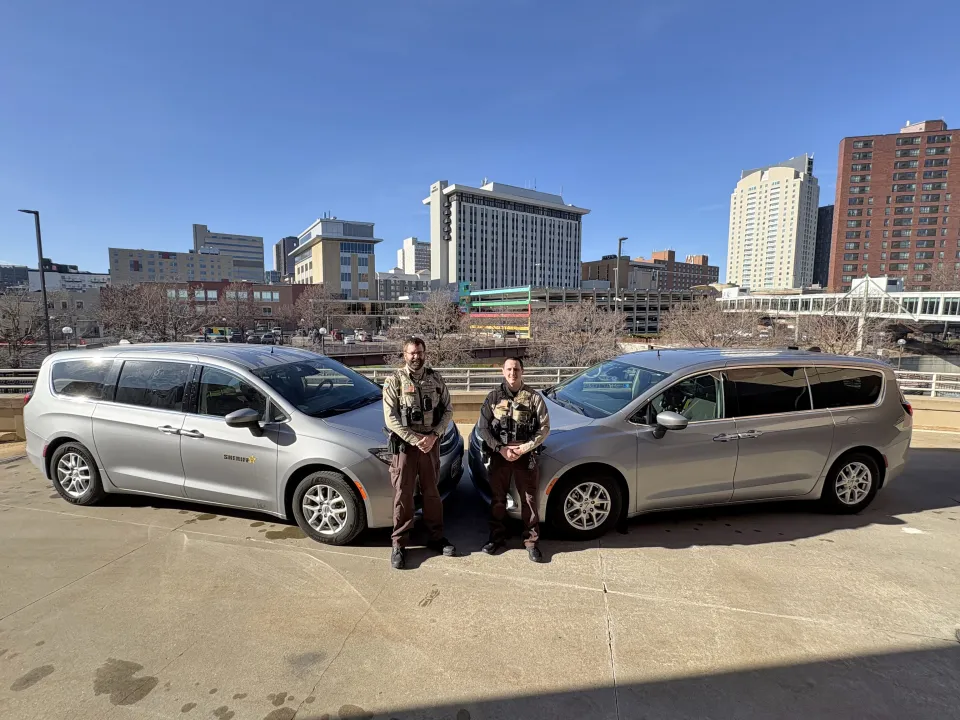 Two members of the Sheriff's Office stand near their transport vans in downtown Rochester