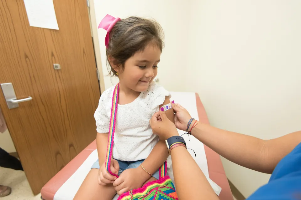 Young child receives a vaccine in a clinic room