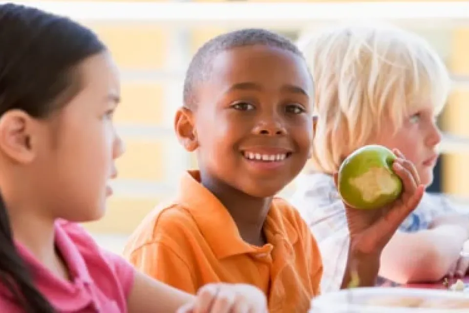 three kids, one eating a apple