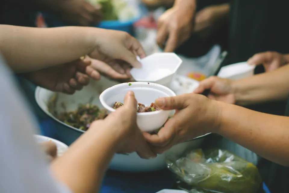 A person handing a bowl of food to another person.