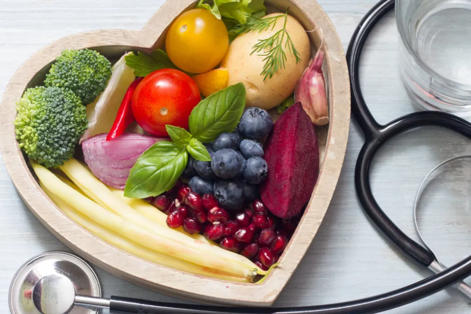 Healthy food in a heart-shaped bowl. A Stethoscope around it.