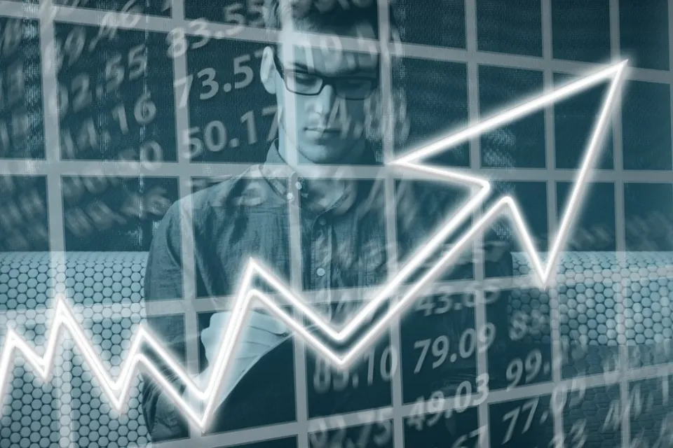 Person analyzing financial data with an upward trending graph superimposed in the foreground, suggesting a focus on stock market analysis or economic growth.