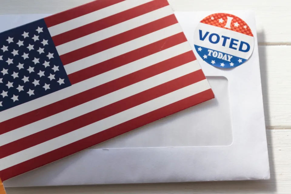 An American flag, a white envelope, and a "I Voted Today" sticker.