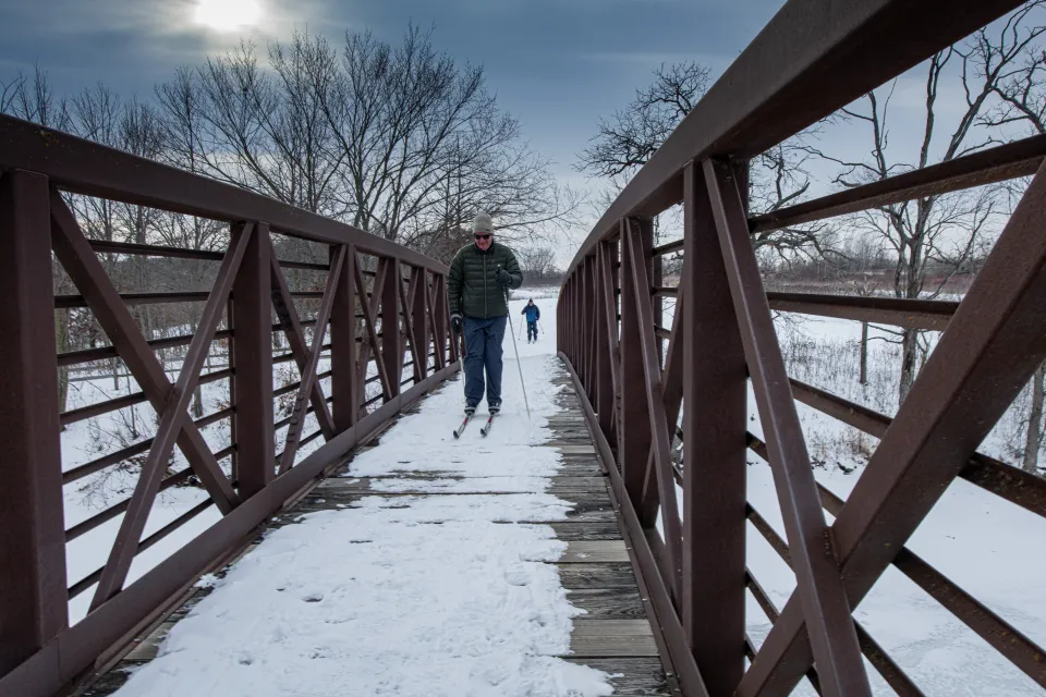 Person cross country skiing over a bridge